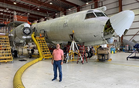 man standing in front of plane in hangar