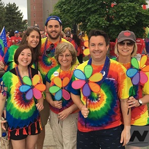 group of employees wearing rainbow shirts pose smiling