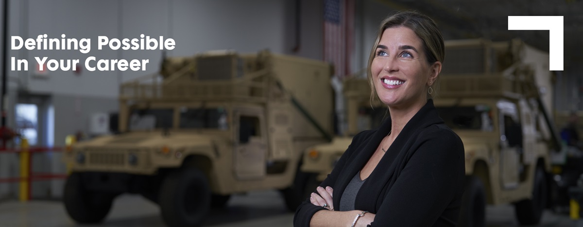 Smiling woman with her arms crossed standing in front of trucks