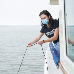female Northrop Grumman employee holding line in water on boat