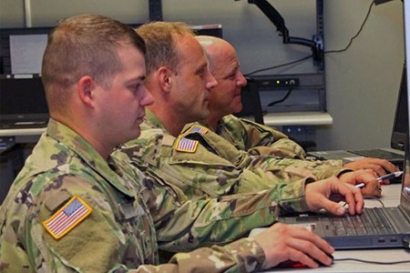 three white men in military uniforms on laptops