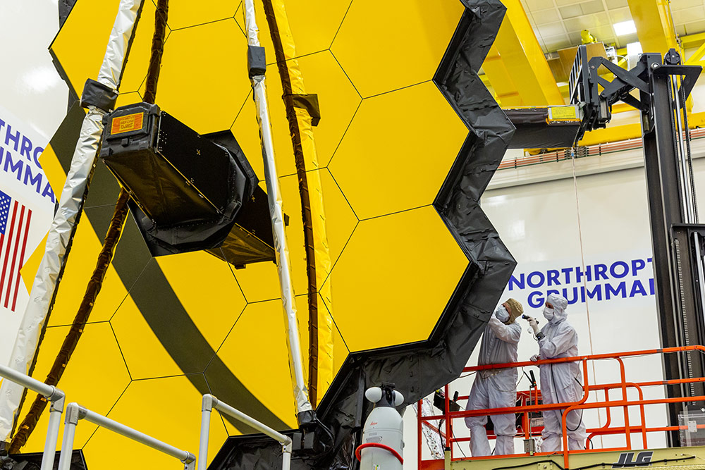 Two engineers in clean suits inspect JWST sunshield panels