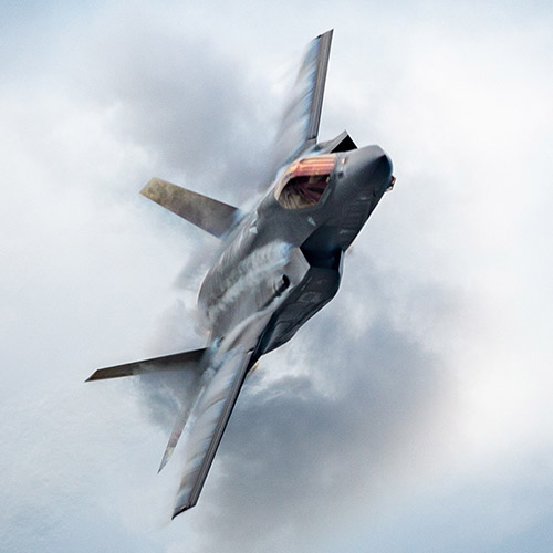 F-35 fighter jet bursting through clouds