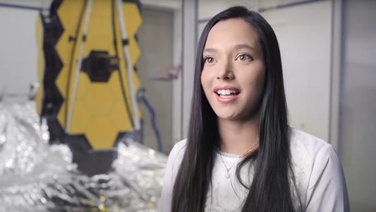 white female smiling in front of space telescope