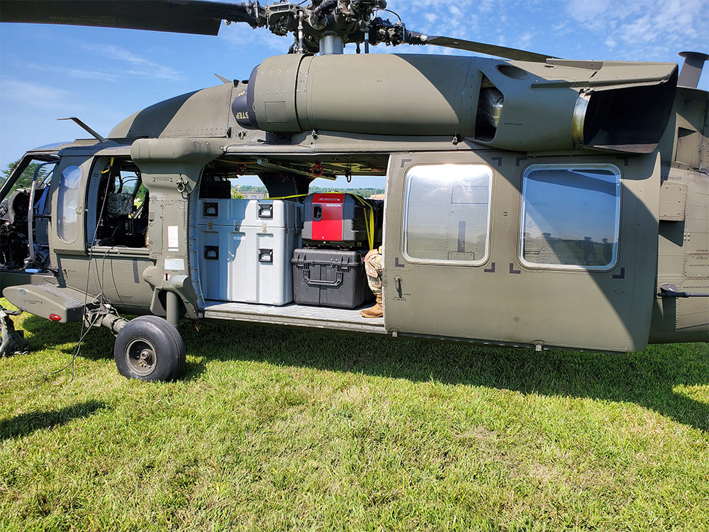Helicopter parked on grass with supplies inside