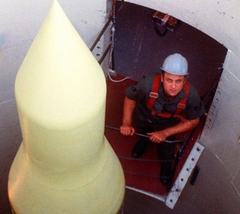 An engineer wearing a hardhat standing next to a missile