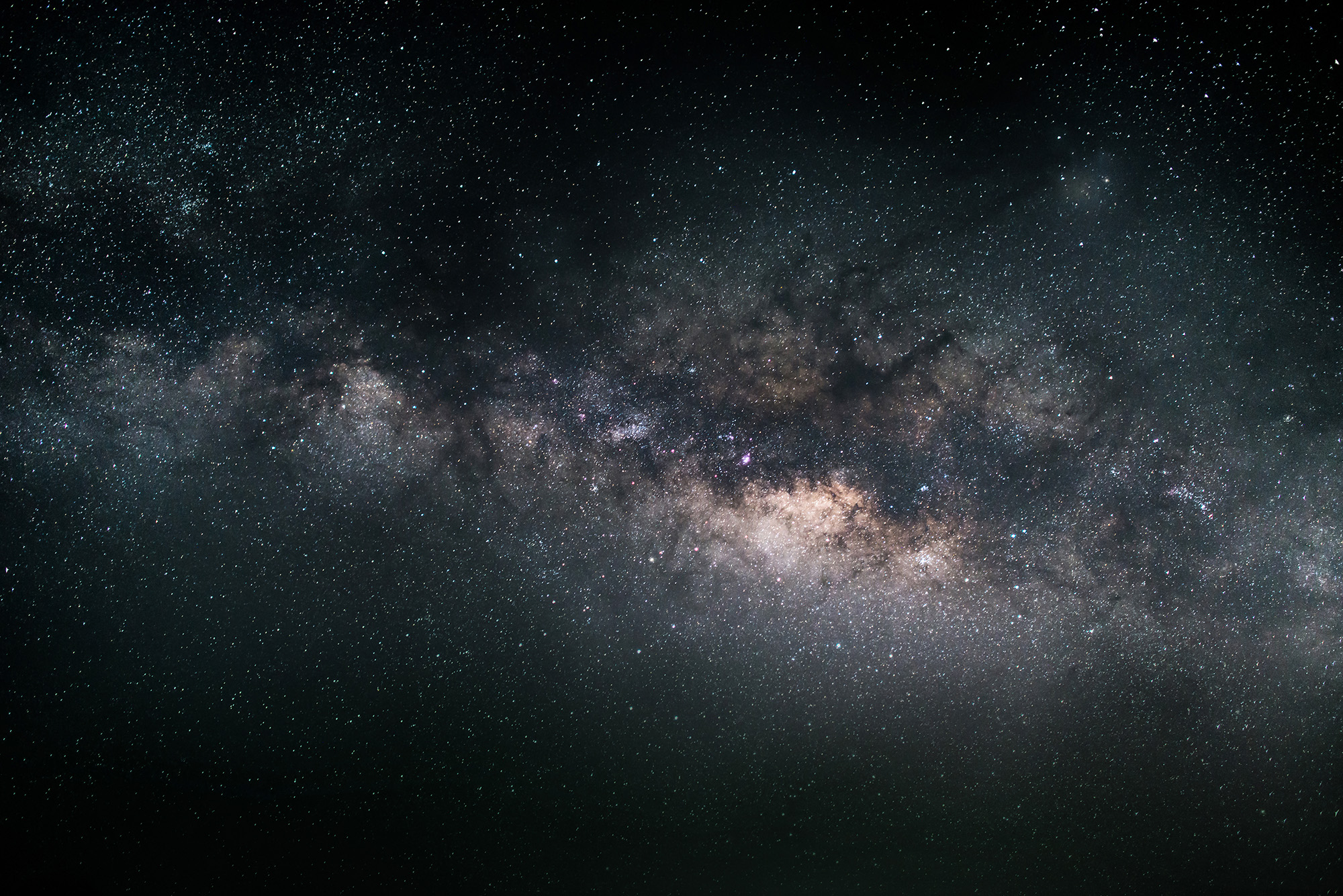 An outerspace view of the milkway in front of a dark star-filled sky