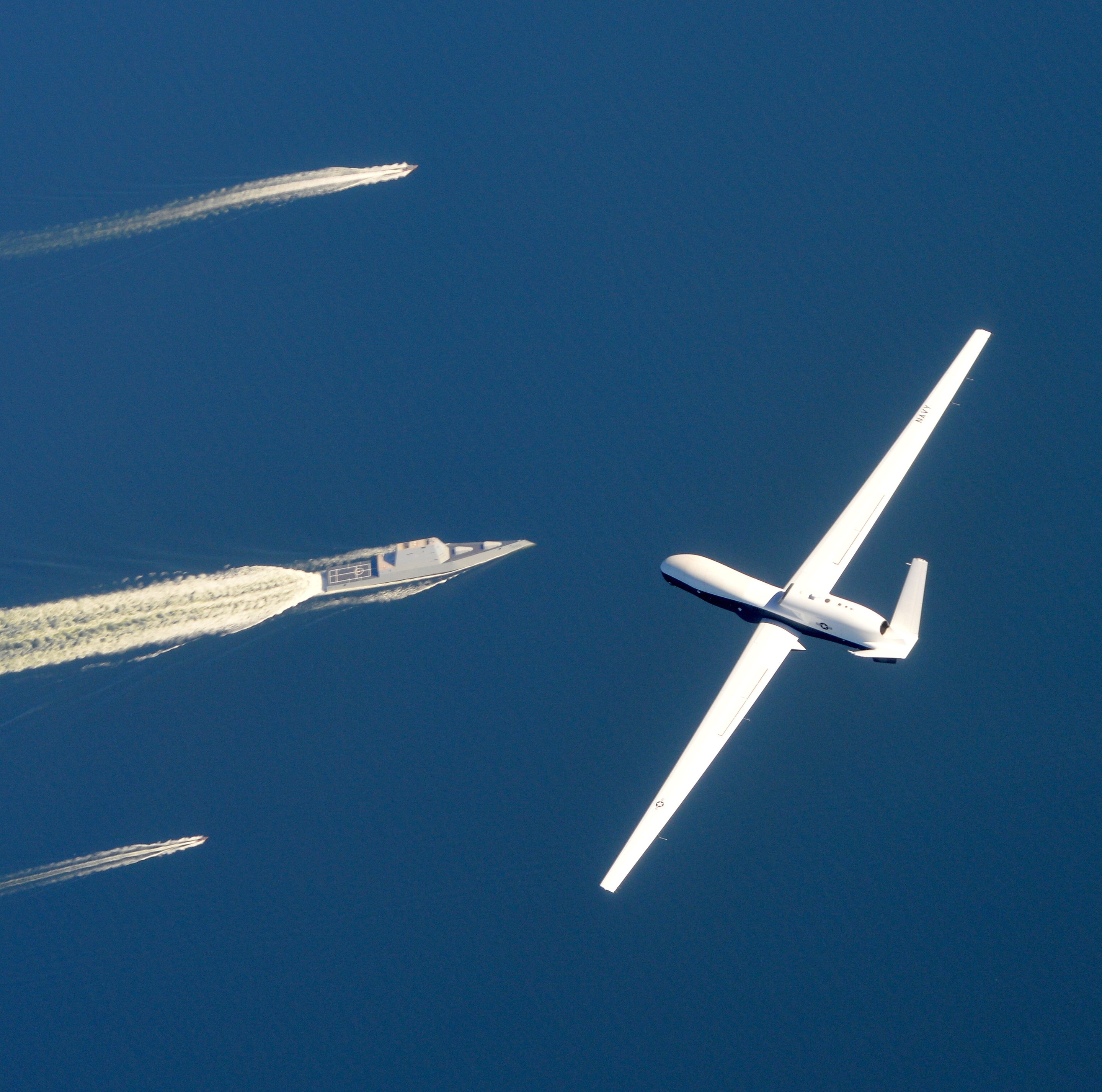 Aircraft in flight over ocean with 3 boats