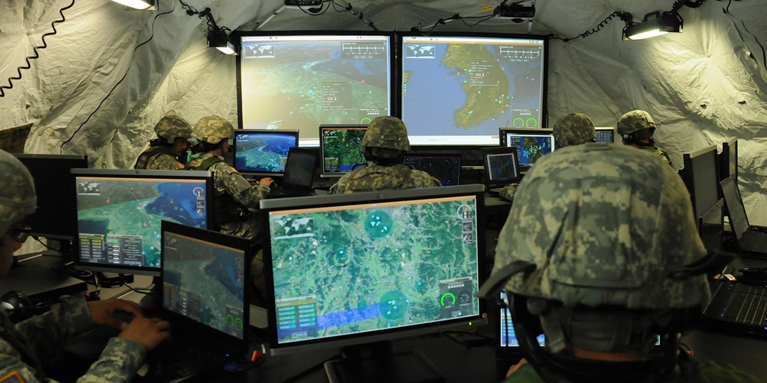 soldiers in tent looking at computer monitors