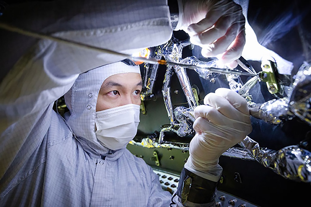 Asian man works on large part of space telescope