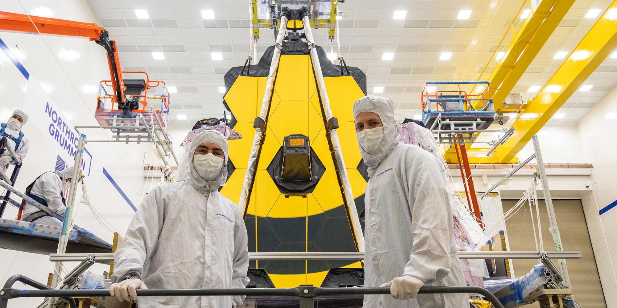 two engineers standing in front of the Webb telescope