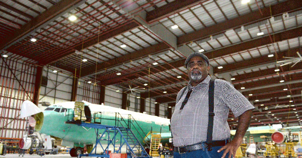 a man stands in front of an airplane in a hangar