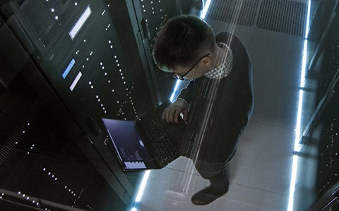 man holding laptop in server room