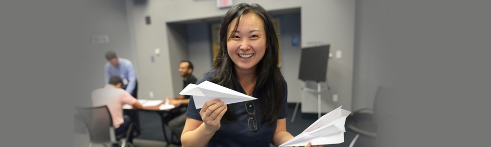 Asian woman smiling holding paper airplane