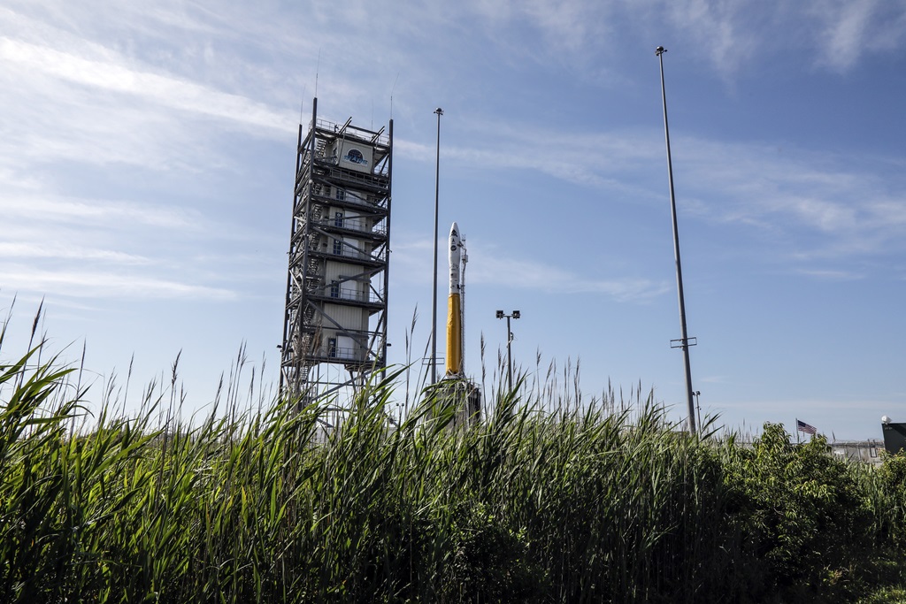 A rocket on a launch pad in front of a blue, light cloudy sky