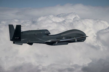 Unmanned military aircraft flying against clouds