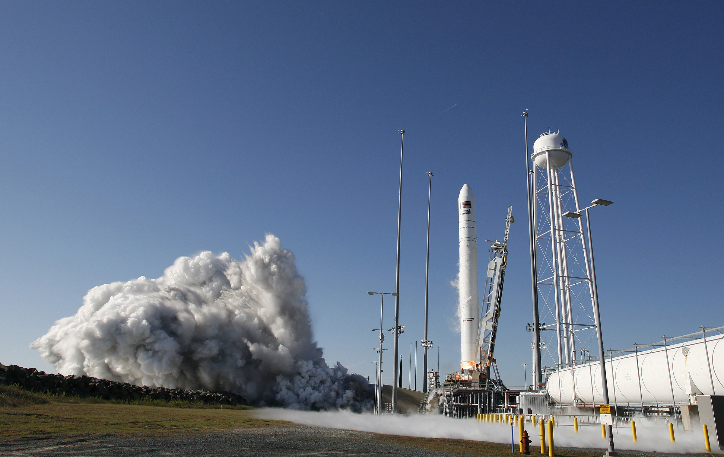 A rocket beginning to liftoff from launch pad in front of a blue sky