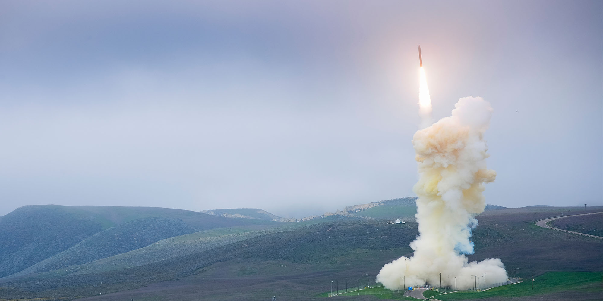 A white missile interceptor launches in front of foggy sky