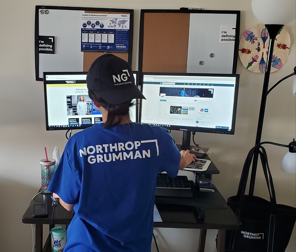 Woman wearing Northrop Grumman apparel works at standing desk
