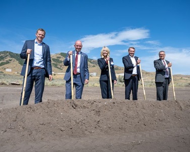 five peole standing in dirt mound with shovels