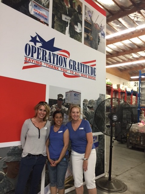 Three females posed by Operation Gratitude wall sign