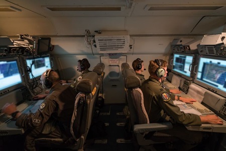 Air crewmen monitor data from computers on an airplane