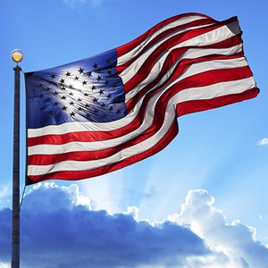 American flag flying in blue sky and clouds in background