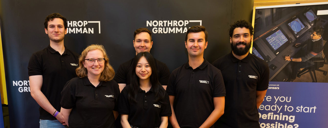 Northrop Grumman employees smile in group photo at recruiting fair. 
