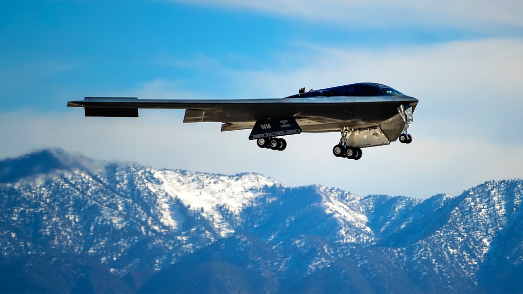 B-2 Spirit Stealth Bomber flying with snow capped mountains in background