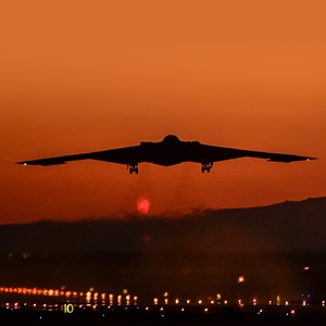 b-2 bomber flying into a red sky at sunset