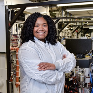 Black woman smiling in white lab coat with arms crossed