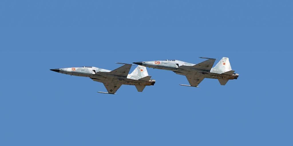 Two F-5 Tiger fighter jets soaring in the blue sky