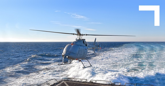 Unmanned helicopter flying above a landing pad in the sea