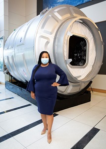 Black woman in front of Cygnus spacecraft