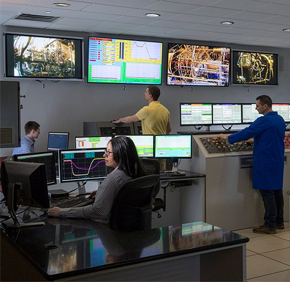 control room with many screens and several people working on computers