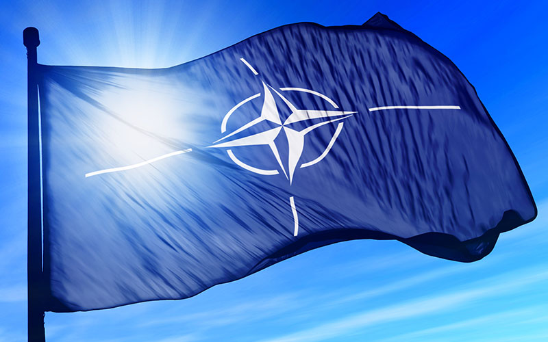blue flag with NATO logo on blue sky