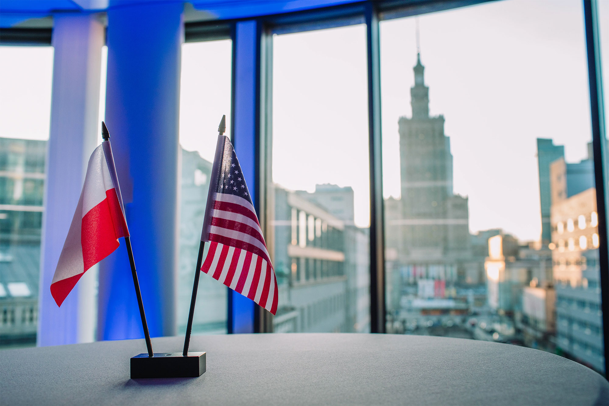 Poland and US flags sitting on a desk.