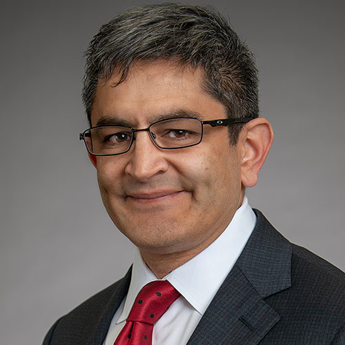 headshot of man in suit wearing glasses