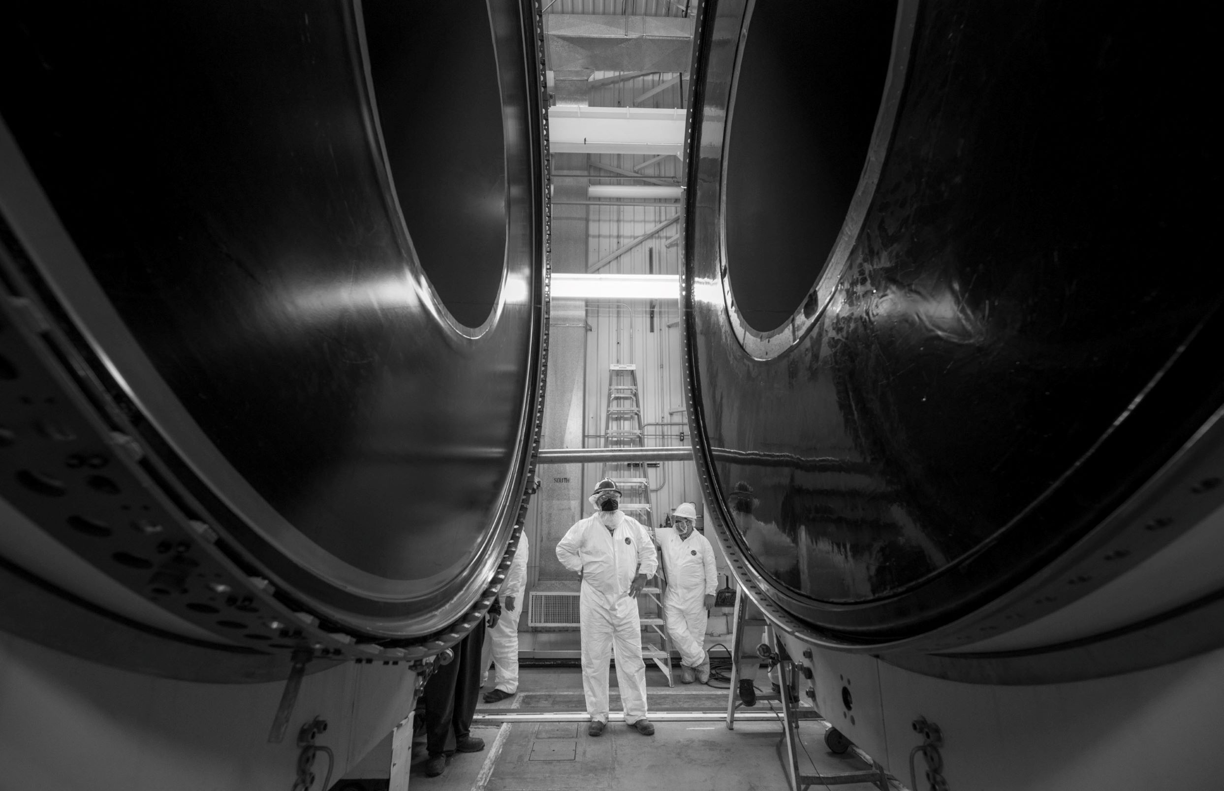 A engineer stands in between the center of a rocket motor inside a facility