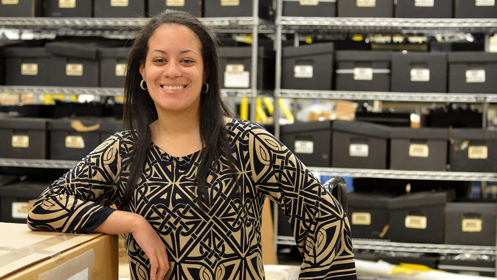 smiling black woman standing in front of shelves