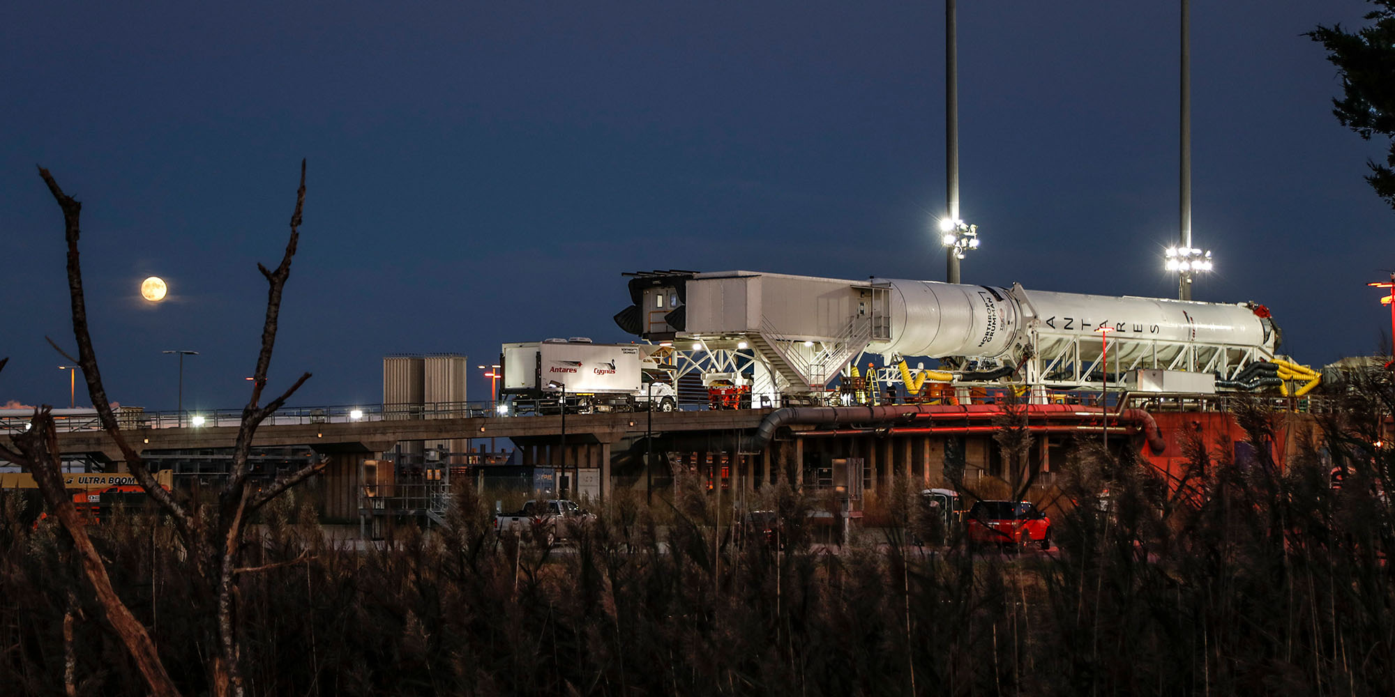 Night shot with moon of the Antares Rocket belly up on launchpad in Wallops Island, Virginia