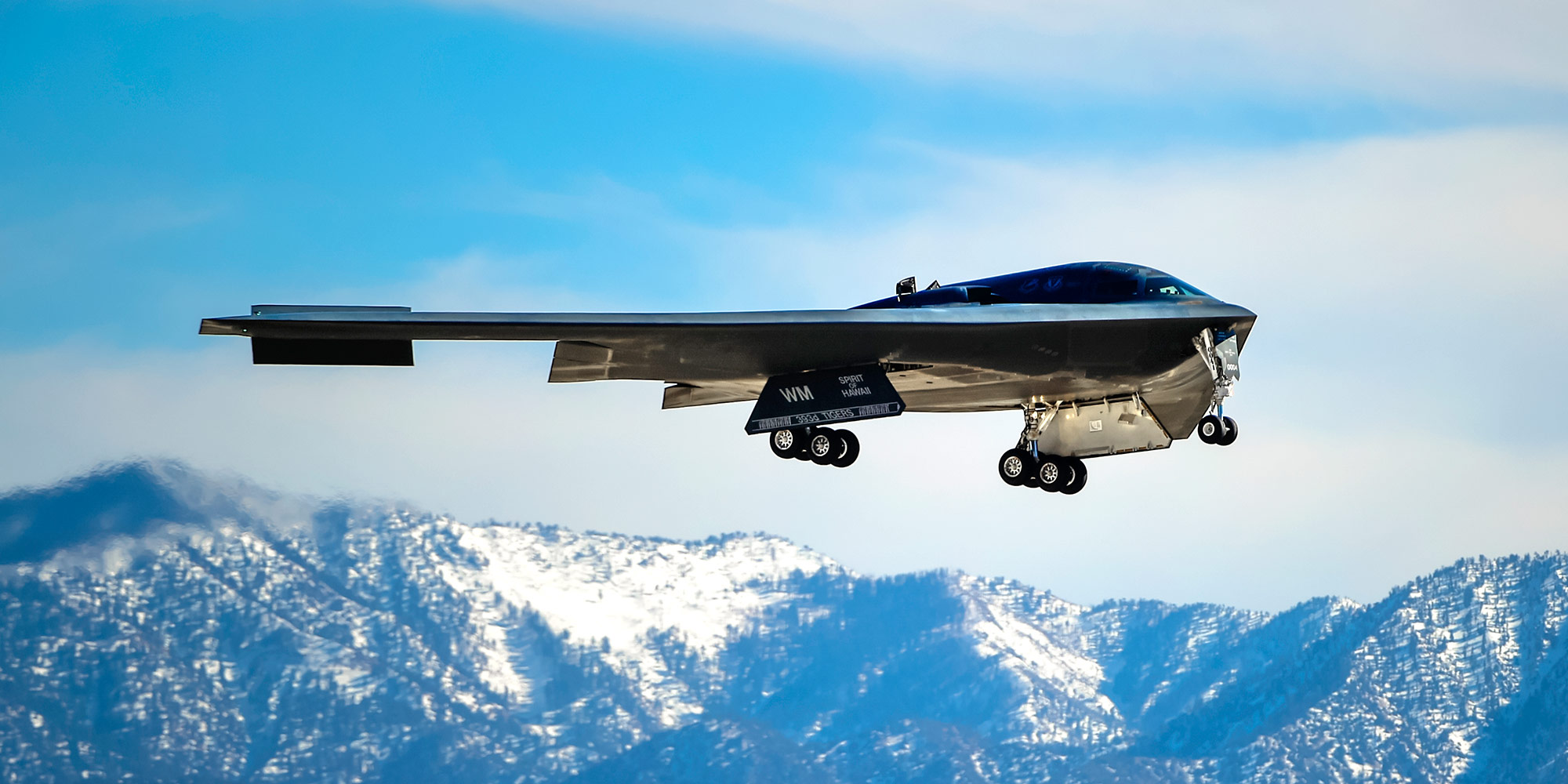 B-2 Spirit Stealth Bomber flying with snow capped mountains in background