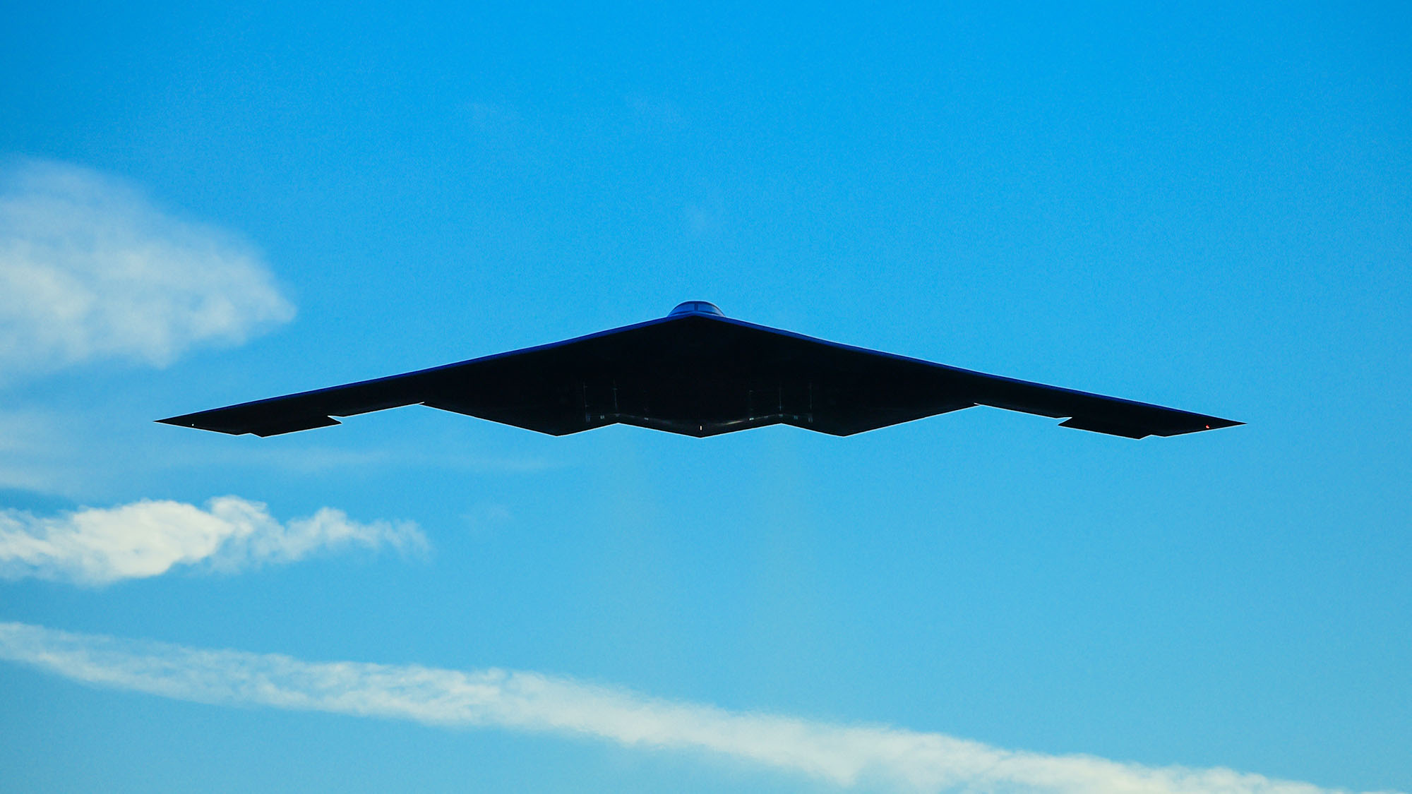 B2 bomber flying amongst clouds on blue skies