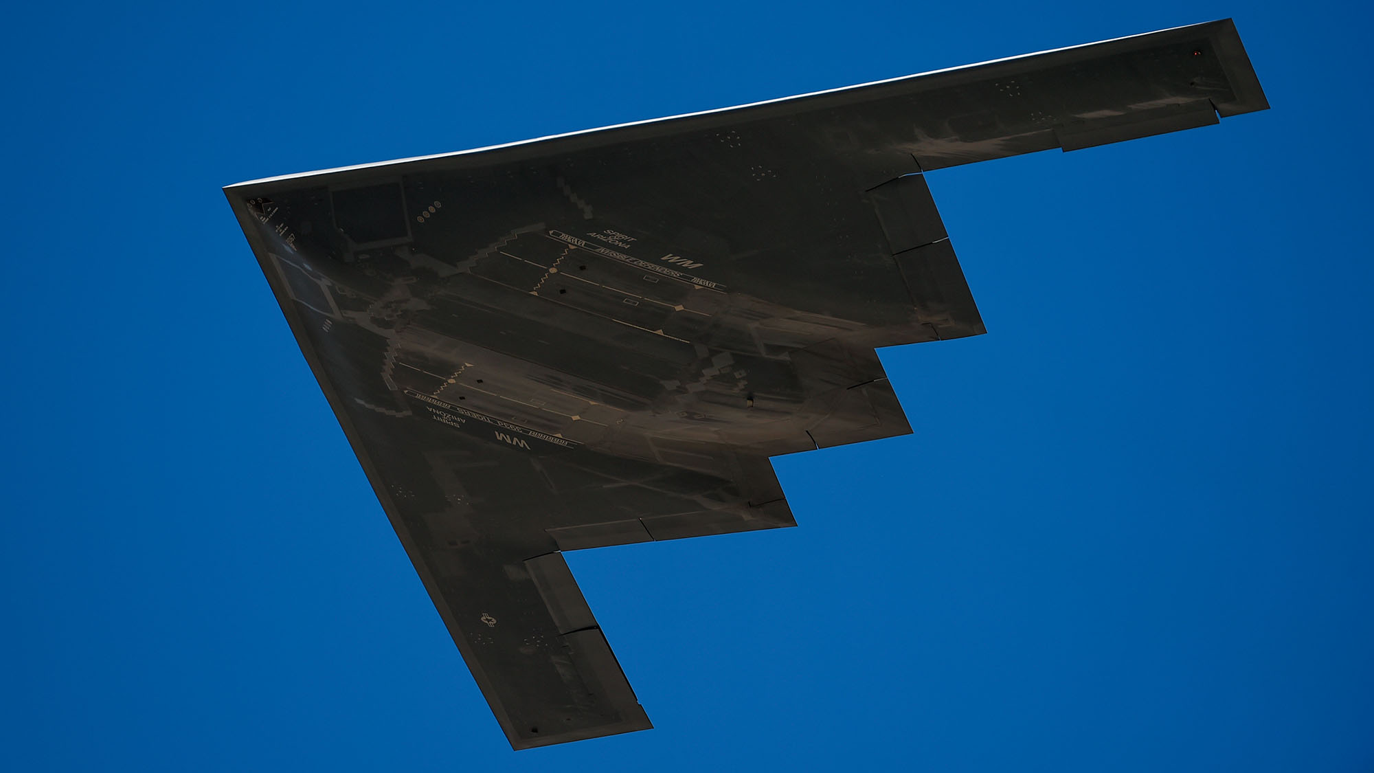 Bottom of B-2 Spirit Stealth Bomber flying in blue skies
