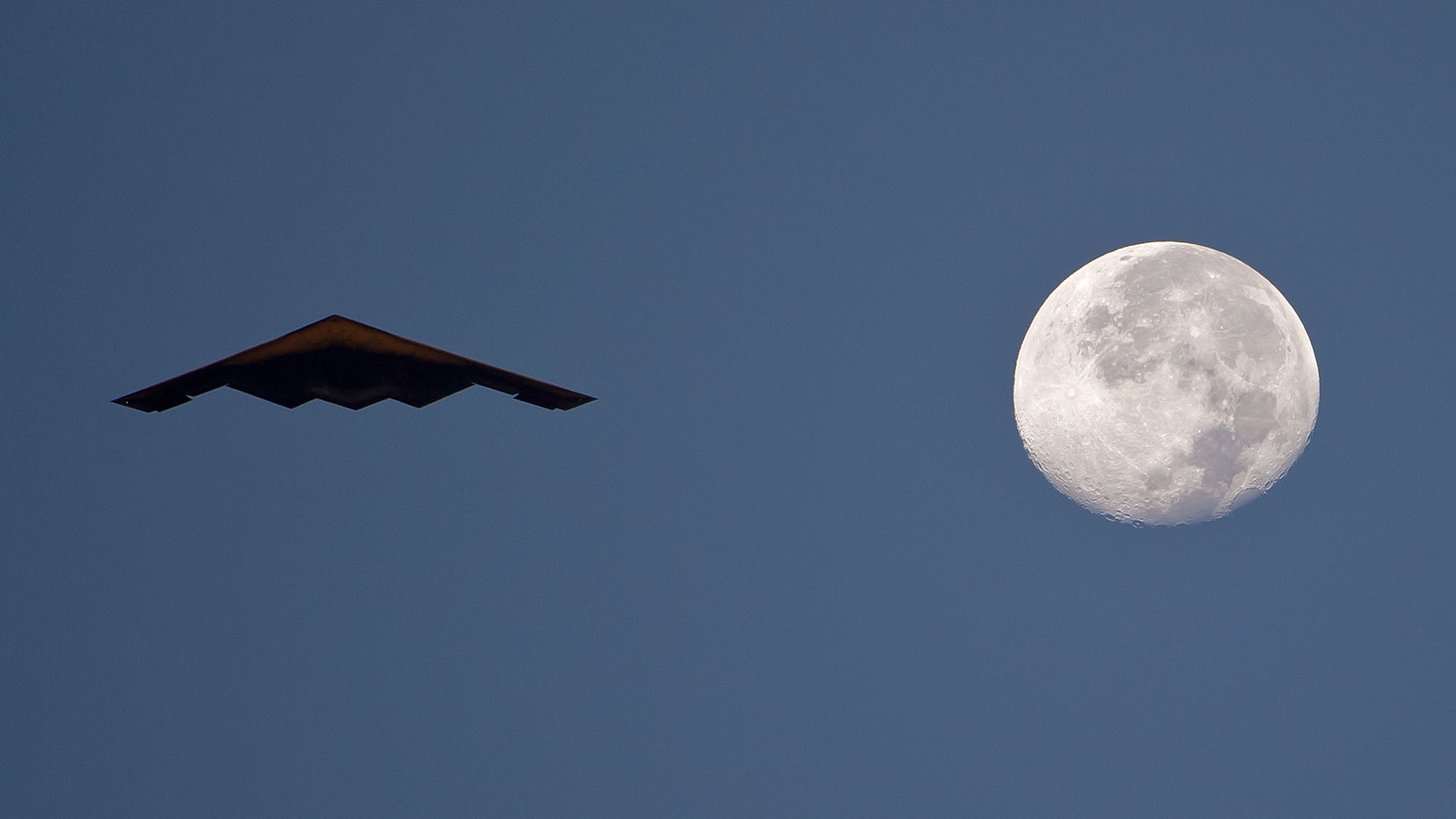 B-2 Spirit Stealth Bomber flying with full moon in sky